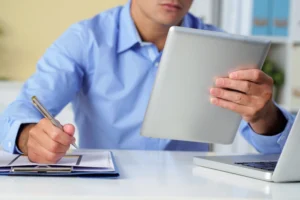 Oznaczanie treści AI, przedsiębiorca sprawdza nowe przepisy przy laptopie i tablecie.